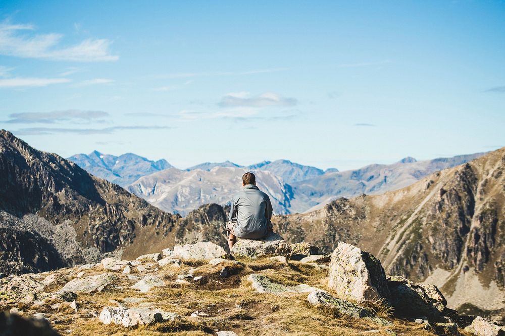 Man sitting on a mountain taking in the views.