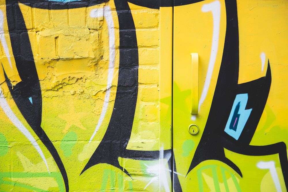 Close up of yellow and black spray painted design on a wall and door.