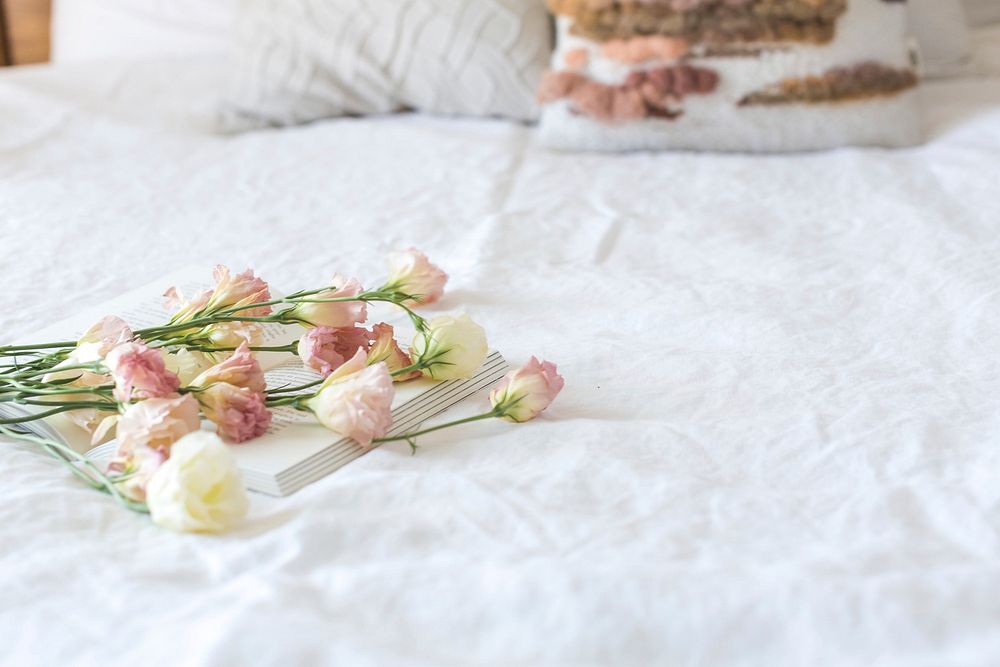 Flowers laid on a book in a bedroom.