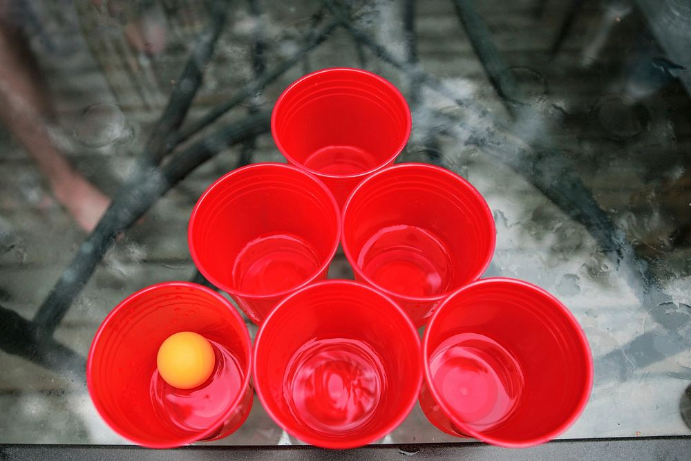 Red plastic cups on a table with a ping pong ball ready for drinking games to be won and lost.
