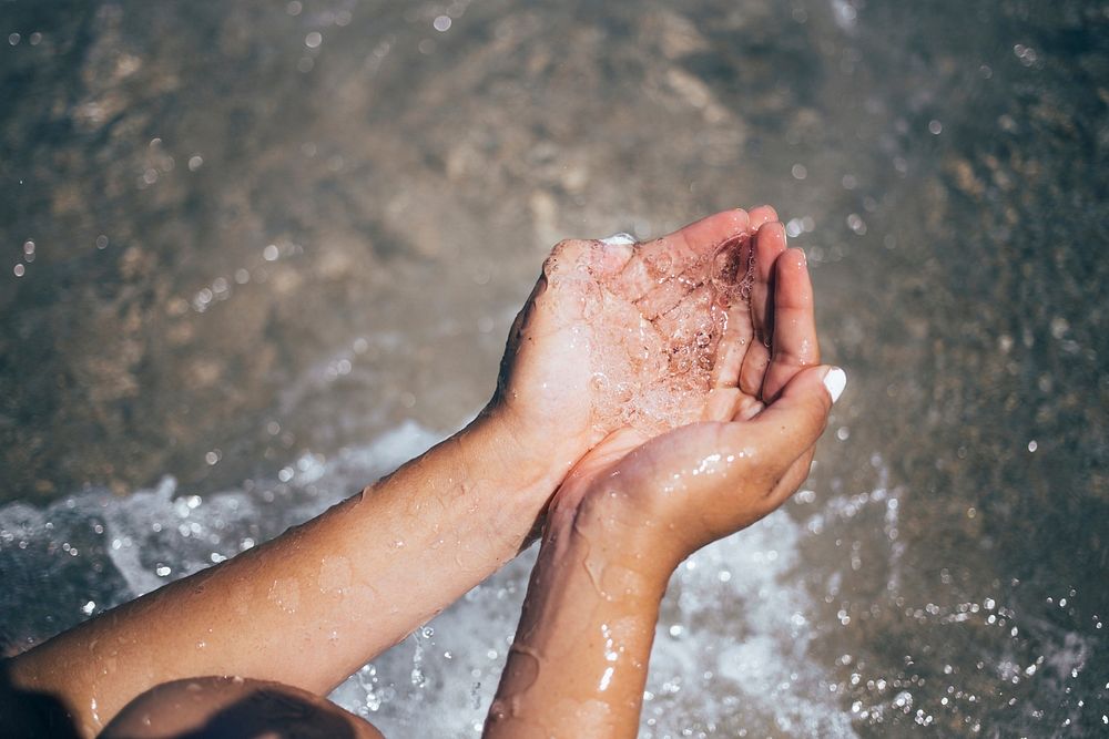 Free clear water falls through a pair of beach goers hands image, public domain people CC0 photo.