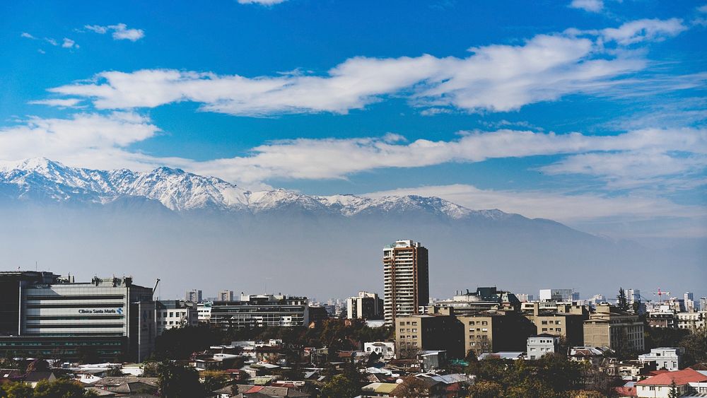 Snowy mountain tops are seen in the background of a modern city.