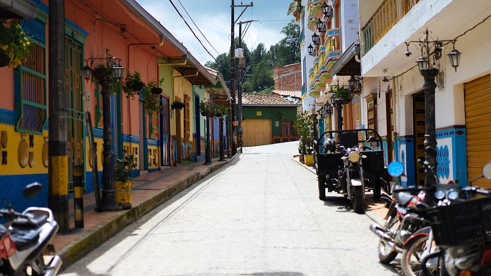 Brightly painted homes and buildings line an uphill city street.