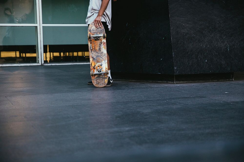 Free person stands with their skateboard in hand beside a city building photo, public domain sport CC0 image.