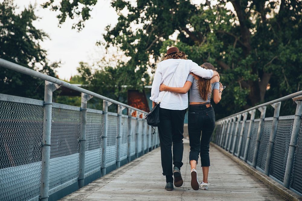 Free young couple walking away on a bridge arm in arm image, public domain CC0 photo.