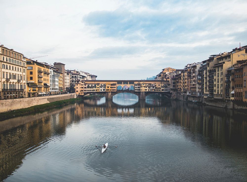 Rowing boat enjoying Florence, Italy as is passes through the city waters.