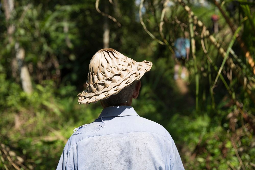 Old man uses a woven hat to protect from the sun's rays.