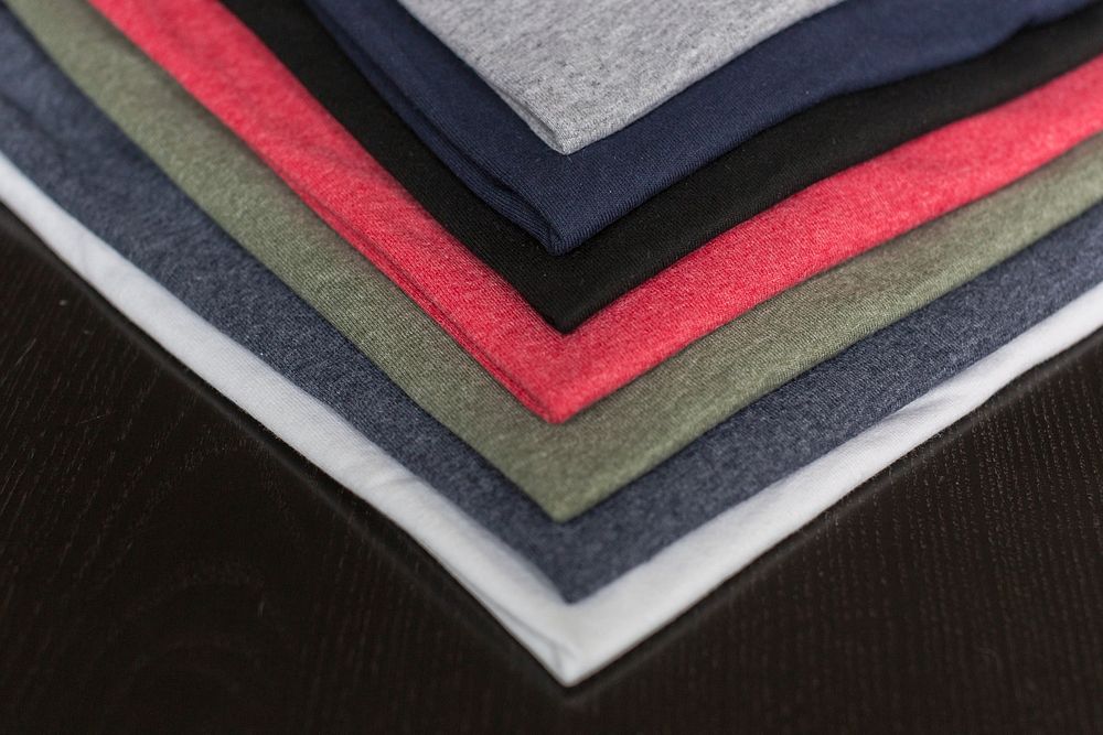 Close up of stack of t-shirts folded on wooden table.