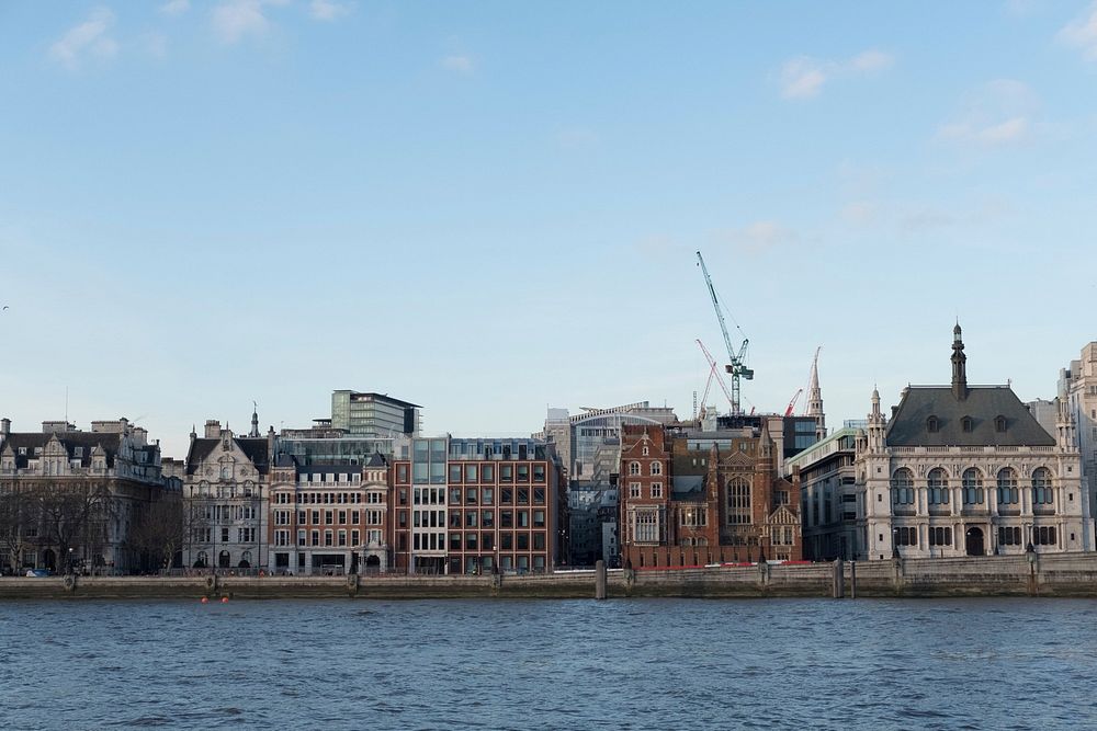 Classic and modern buildings line the water's edge of the Thames in London England.