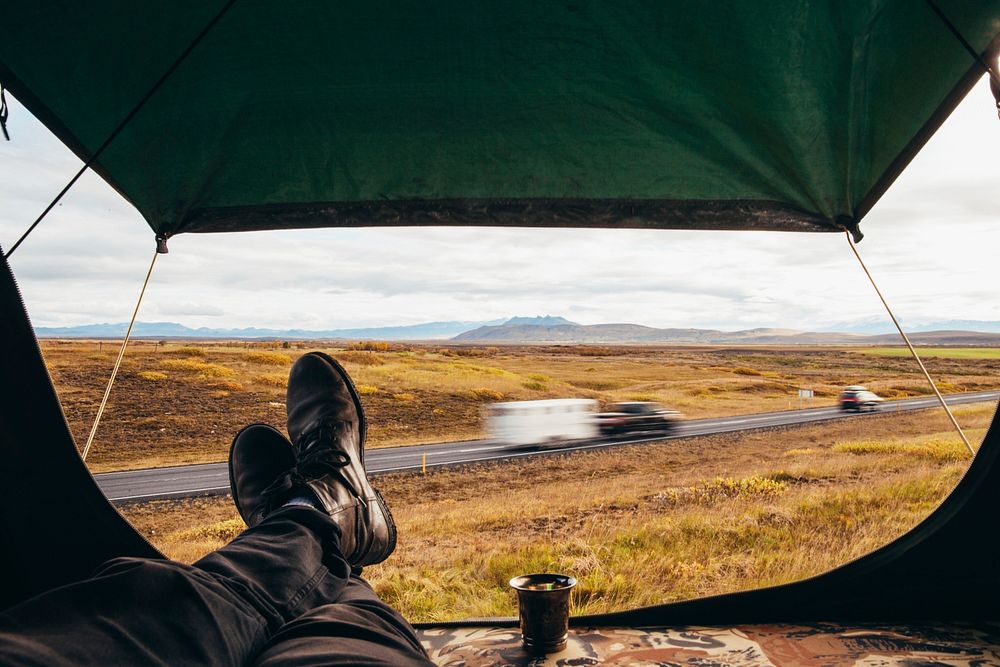 Relaxing in a tent, next to the highway. Camping the Iceland way as other cars race past.