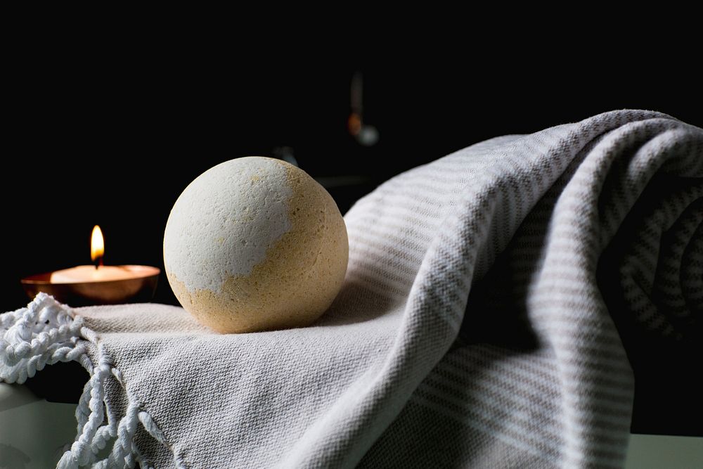 Yellow and white bath bomb on purple towel.