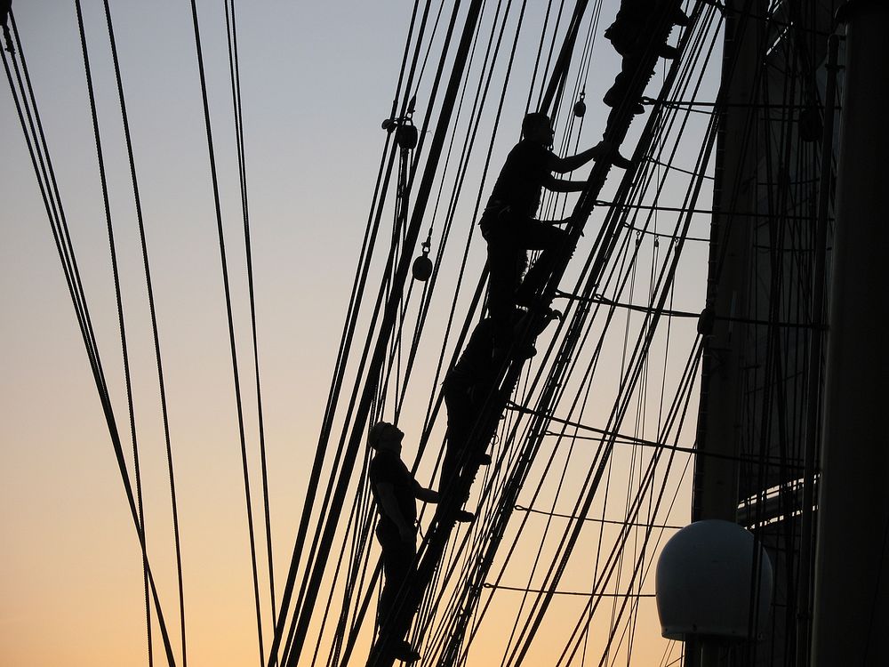 Crew member climbing up during sunset. Original public domain image from Flickr