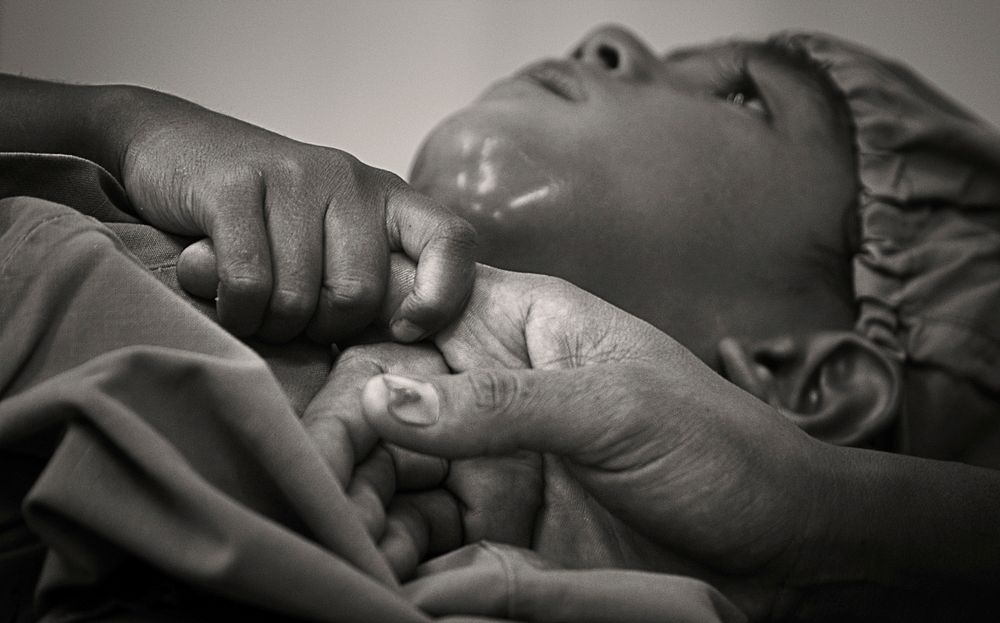 A 4-year-old boy grips his mother's hand before undergoing surgery to remove decayed teeth and drain an infection in his…