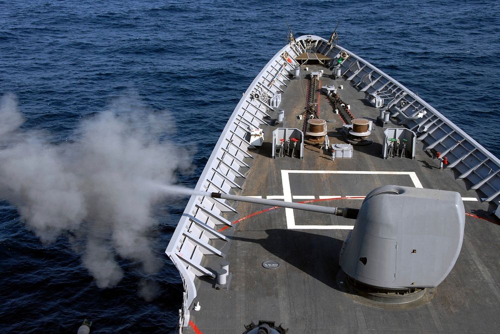 An Mk-45 five-inch .54-caliber gun is fired aboard guided-missile cruiser USS Chosin (CG 65) during a training exercise…