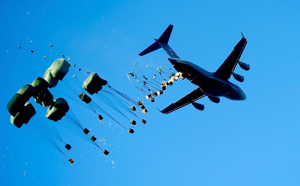 A U.S. Air Force C-17 Globemaster III aircraft drops pallets of water and food over Mirebalais, Haiti, Jan. 21, 2010, to be…