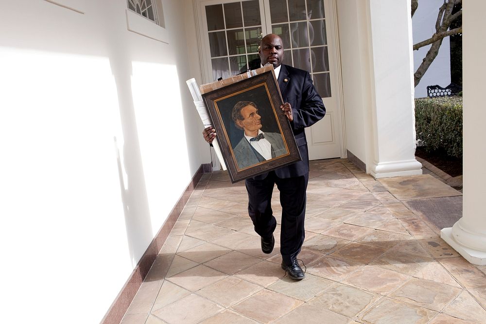 Rob Robinson from the Correspondence Office walks on the Colonnade carrying a gift portrtait of Abraham Lincoln to the West…