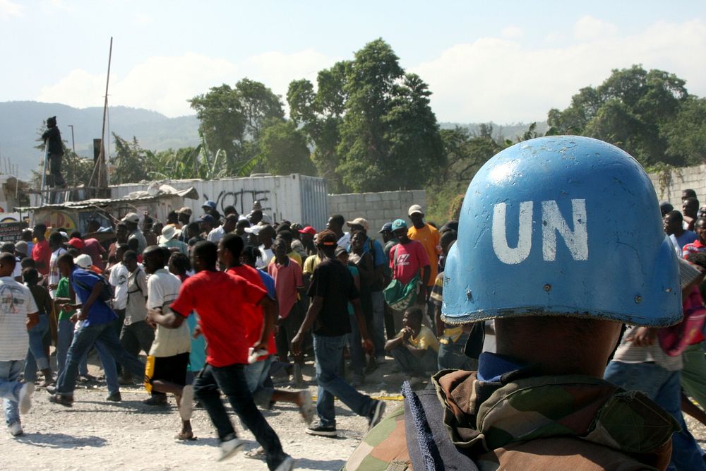 A Sri Lanka soldier attached to the United Nations forces in Haiti watches as a mob-like crowd surges to the check point…