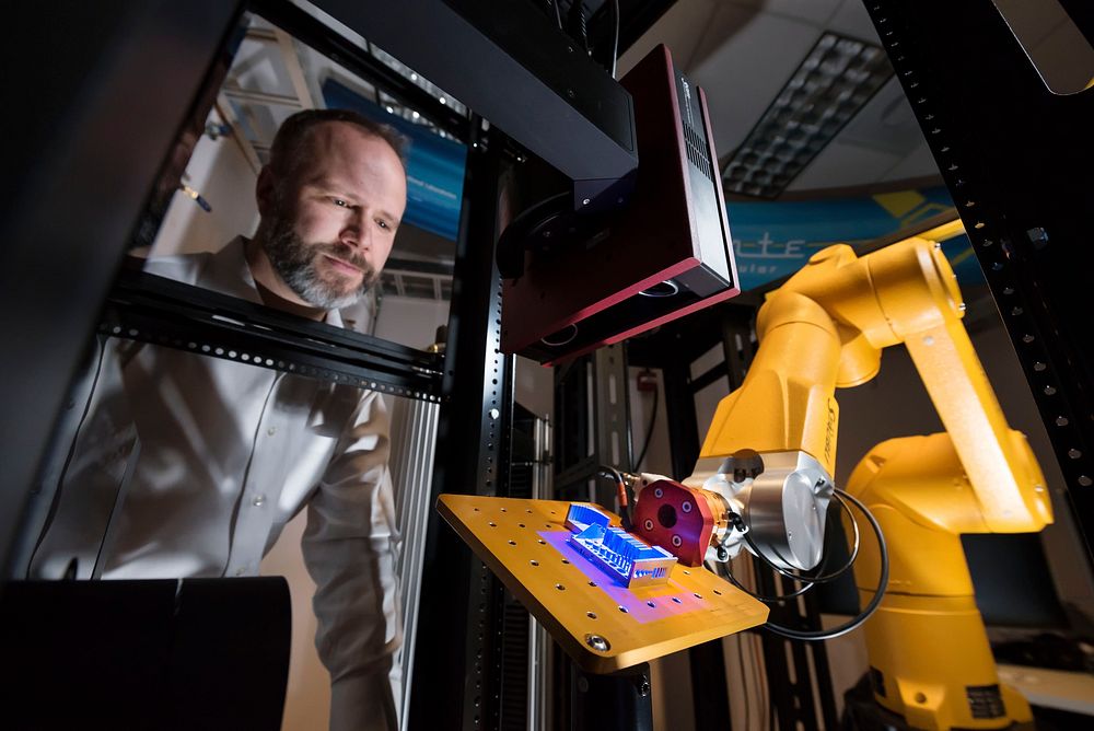 Sandia National Laboratories materials scientist watches as the Alinstante robotic work cell scans a 3D-printed part to…