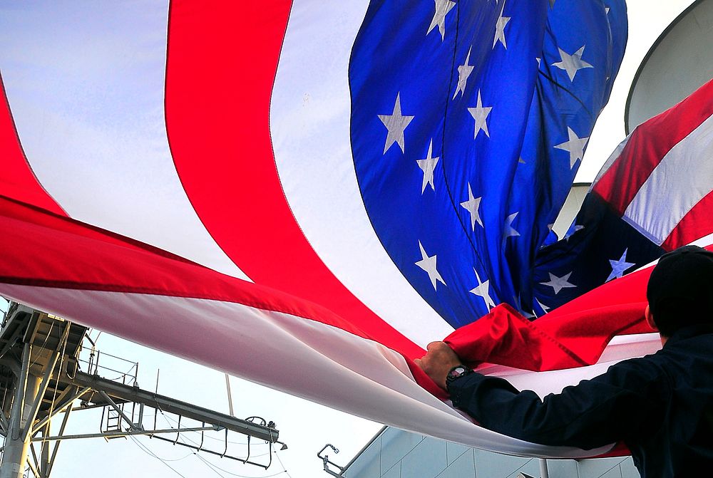 U.S. Navy Quartermaster Seaman Matthew Rivera lowers the battle flag aboard the guided-missile cruiser USS Bunker Hill (CG…