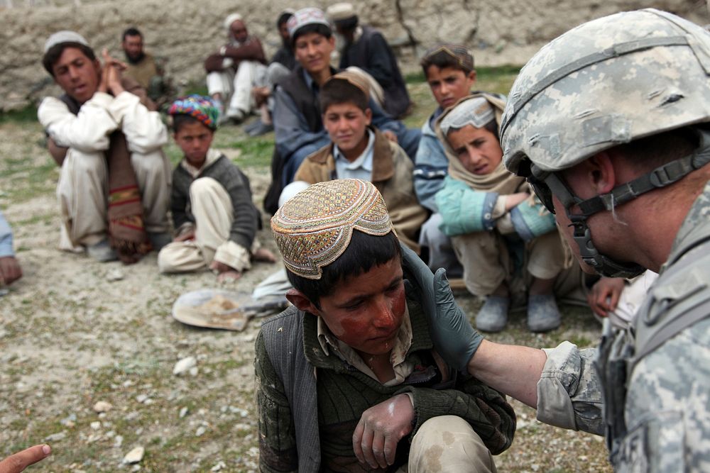 A U.S. Army medic treats an Afghan child for sunburn in the village of Meryanay in the Kherwar district of the Logar…