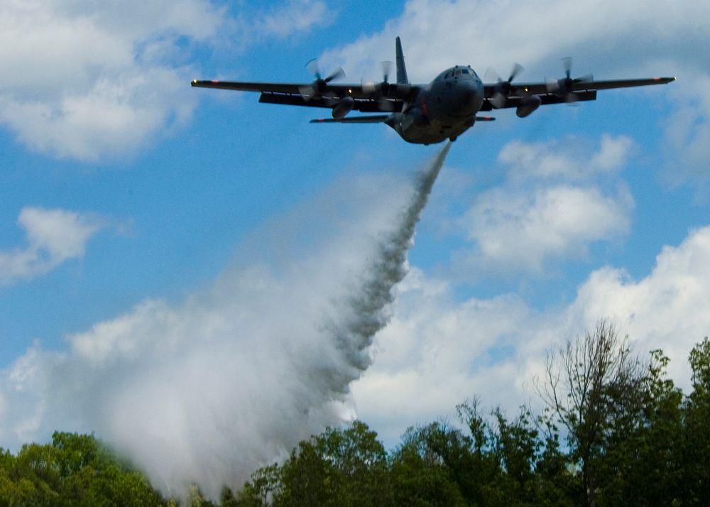 A C-130 Hercules aircraft equipped with a Modular Airborne Firefighting System (MAFFS) drops water over an area in South…