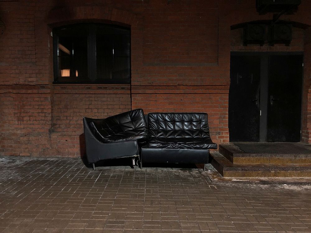 Black couch in front of brick wall. Free public domain CC0 image.
