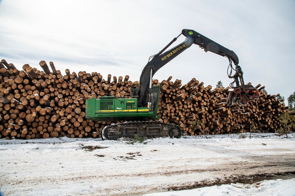 A harvester near tree logs ready to be trucked to a nearby mill, at the U.S. Department of Agriculture (USDA) Forest Service…