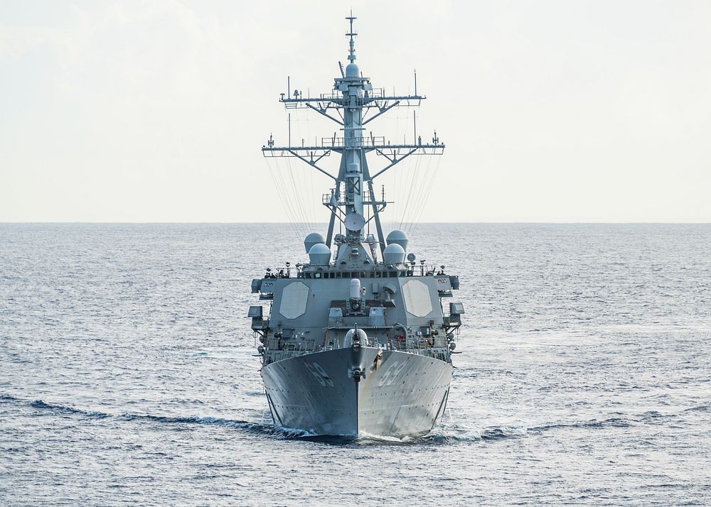 The Arleigh Burke-class guided-missile destroyer USS Milius (DDG 69) sails behind the amphibious dock landing ship USS…