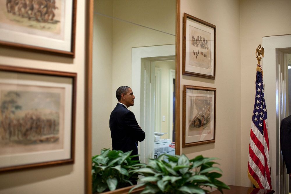 President Barack Obama is reflected in a mirror in a hallway in the West Wing of the White House, June 23, 2010.