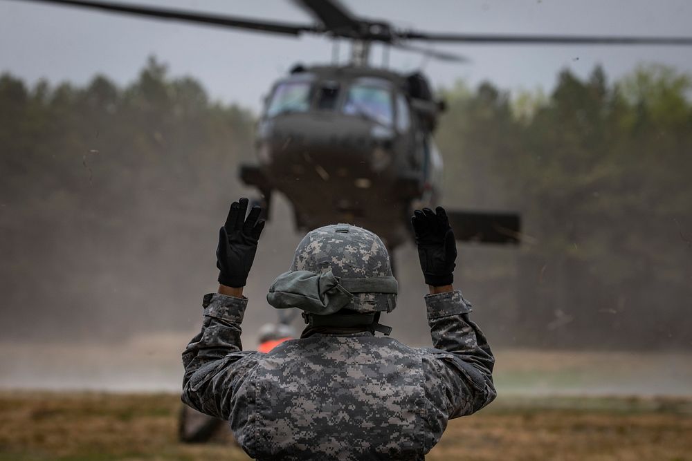 A U.S. Army National Guard Soldier from New Jersey’s 250th Brigade Support Battalion signals to a UH-60M Black Hawk…