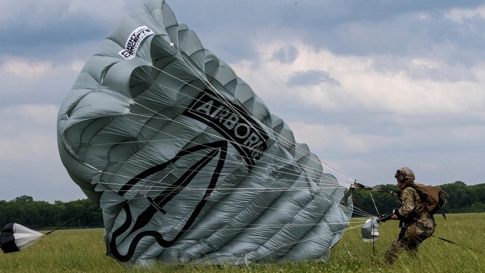 A Soldier, from the U.S. Army Special Operations Command Black Daggers Parachute Demonstration Team gathers his parachute…