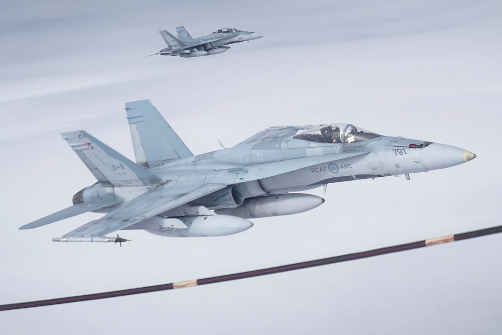 Two Royal Canadian Air Force CF-18 Hornets pull up to a CC-150 Polaris refueling tanker as RCAF Airmen assigned to the 437th…