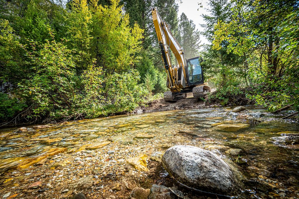 U.S. Forest Service Road Crew Supervisor J.S. Turner excavates a closed bridge to create a crossing for locals near the…