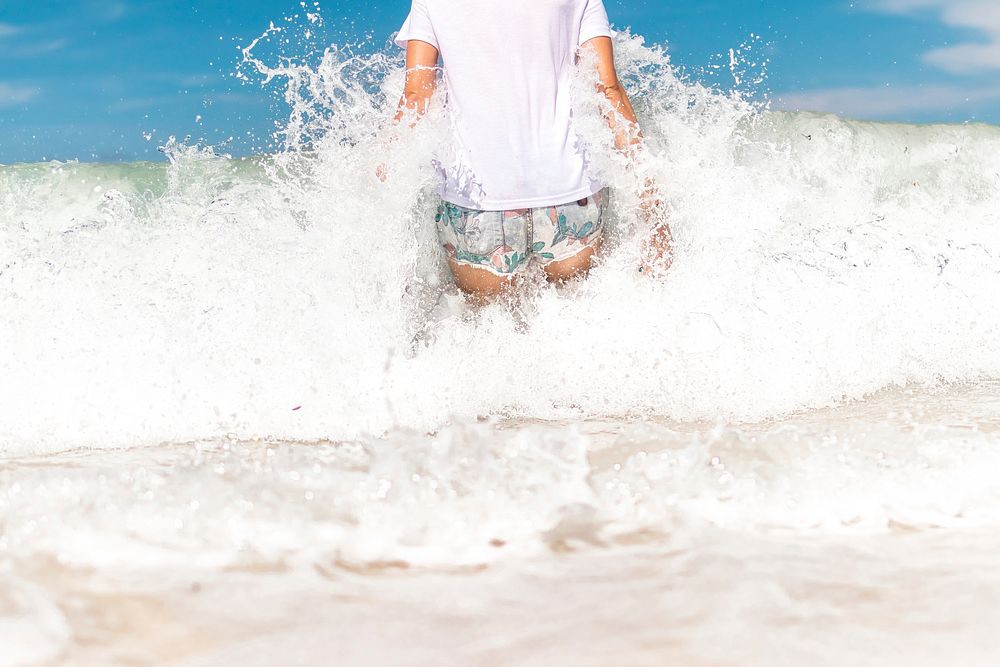 Young woman having fun with ocean waves on a tropical beach of Bali island, Indonesia. Free public domain CC0 photo.