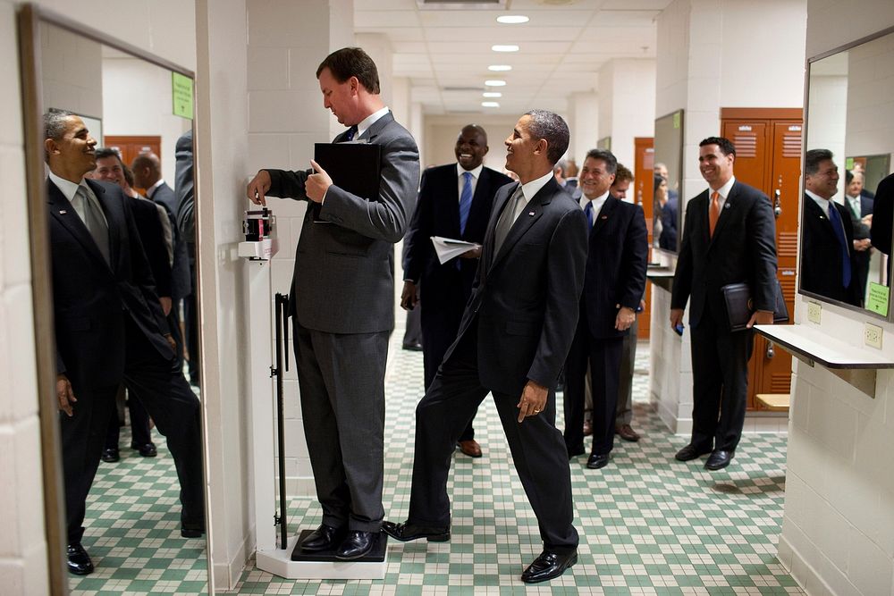 President Barack Obama jokingly puts his toe on the scale as Trip Director Marvin Nicholson, unaware to the President's…