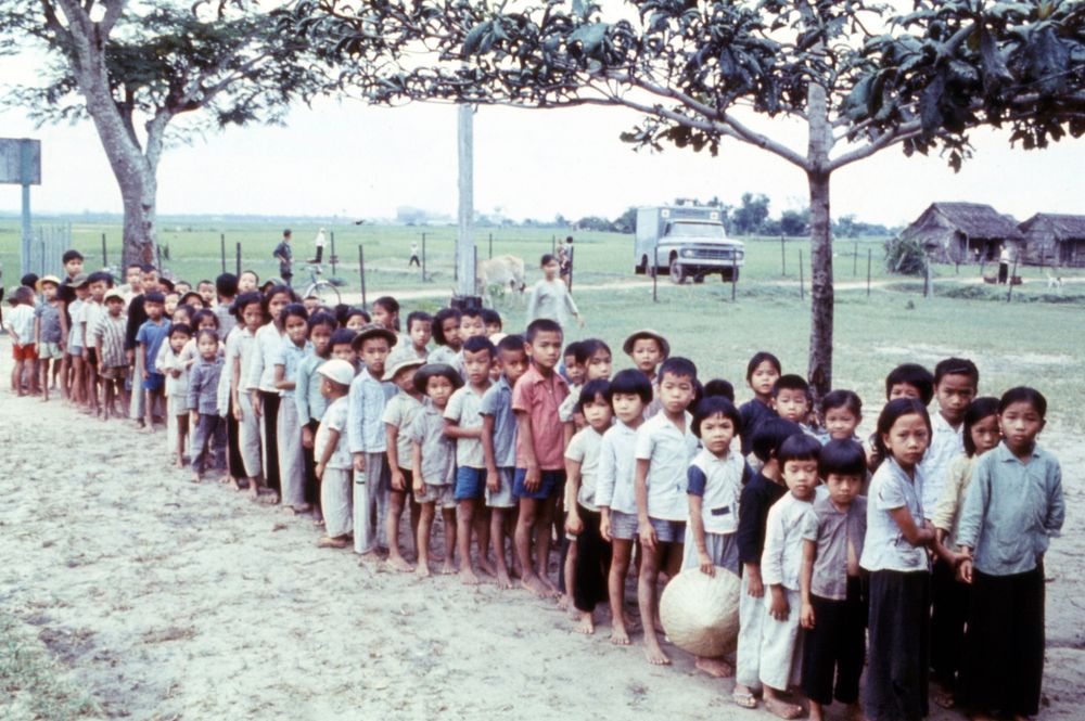 Line waiting to see the dentists at orphanage near Saigon. Cattle in background. [Children][Scene][Foreign…