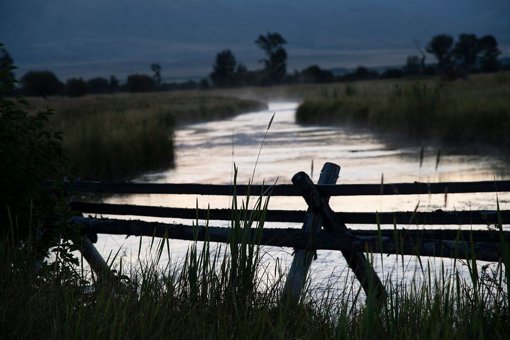 A creeks flow in and out of property marked by wooden split-rail A-frame fence, in Madison County, Montana, on August 29…