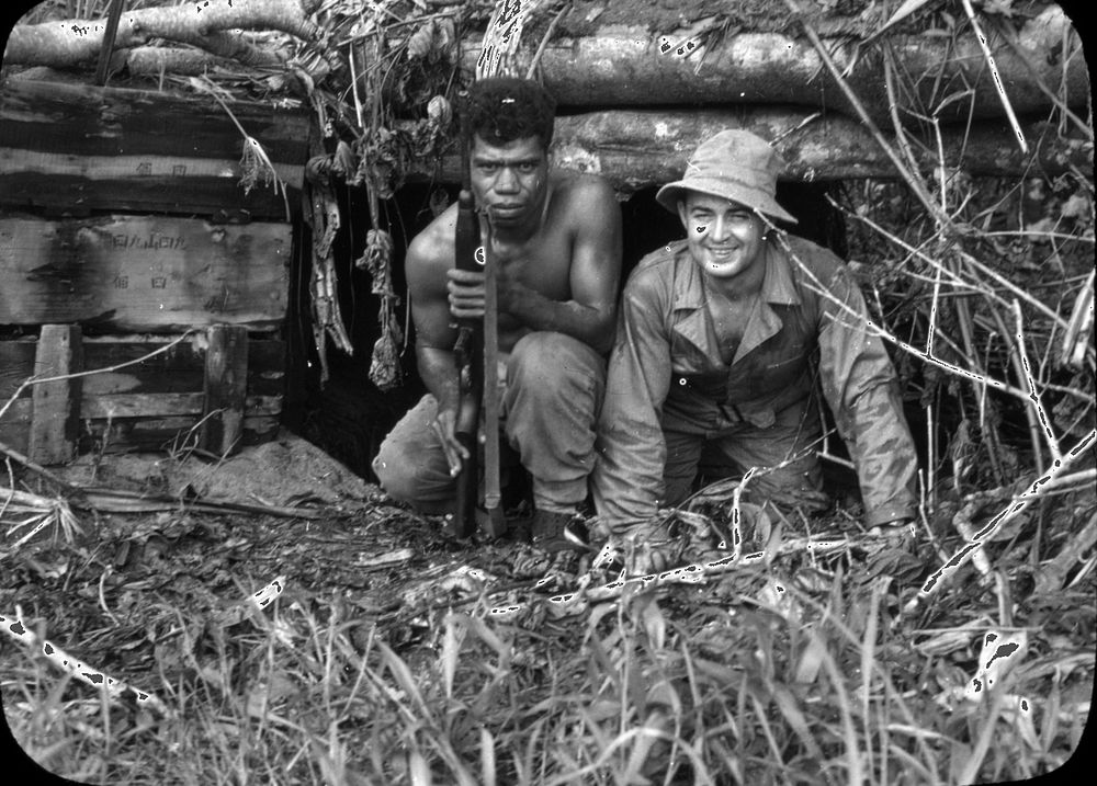Medical personnel pose with a Papua New Guinea military member kneeling in the entrance of a dugout. [Personnel][Foreign…