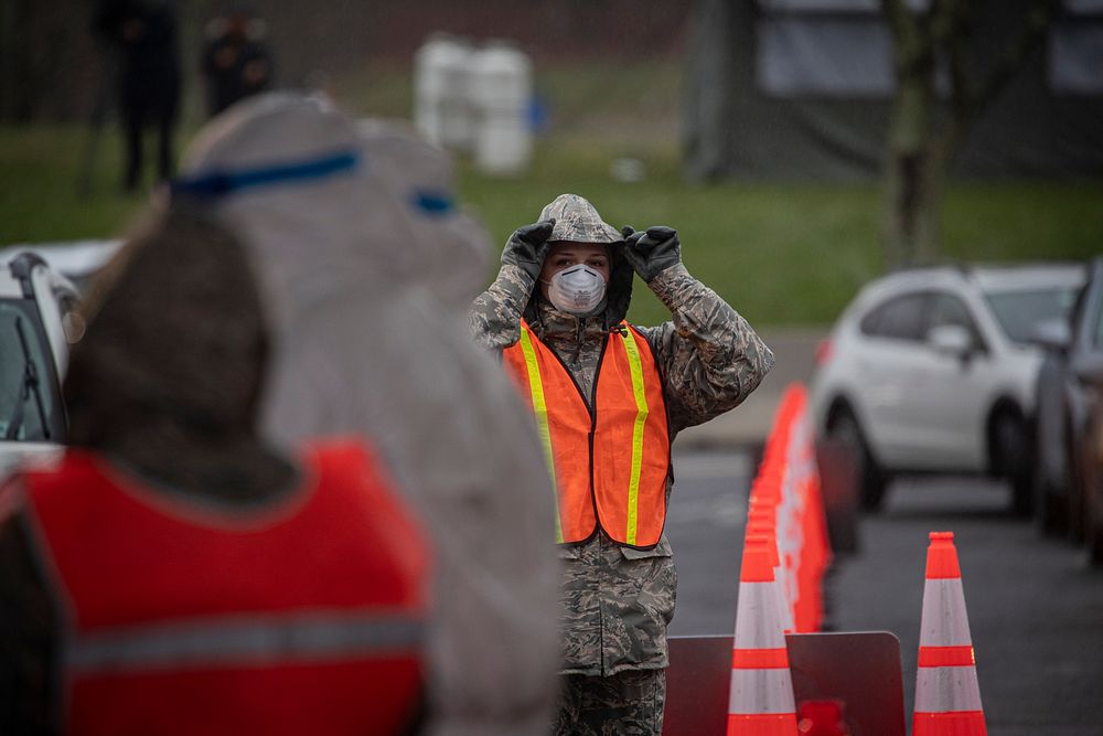 A New Jersey Air Guard Airman from the 108th Wing adjusts her hood while controlling traffic at a COVID-19 Community-Based…