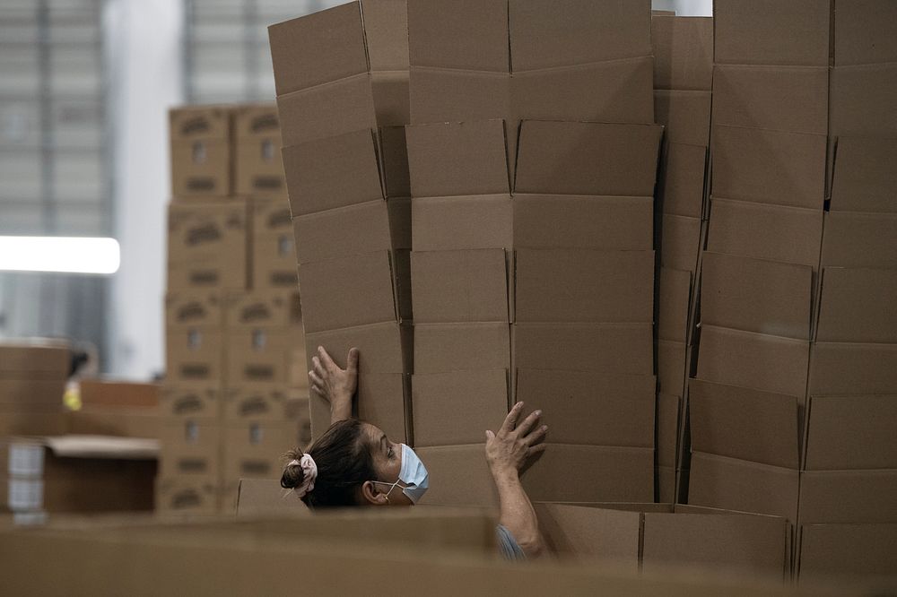 A worker grabs tall stacks of empty boxes to be filled with food, during the U.S. Department of Agriculture (USDA) Secretary…