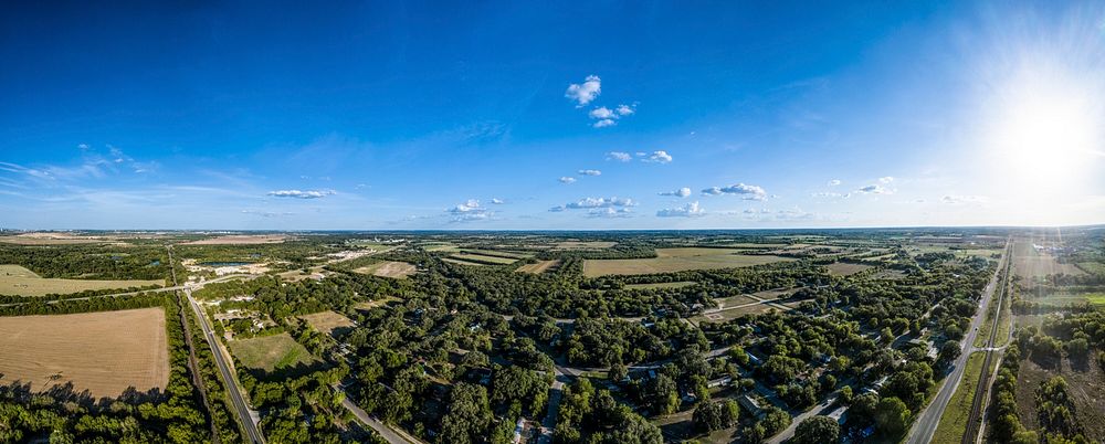 180-degree aerial photo panorama of Macdona, TX, on August 18, 2020. On the far left, hay baling operations at Schirmer…