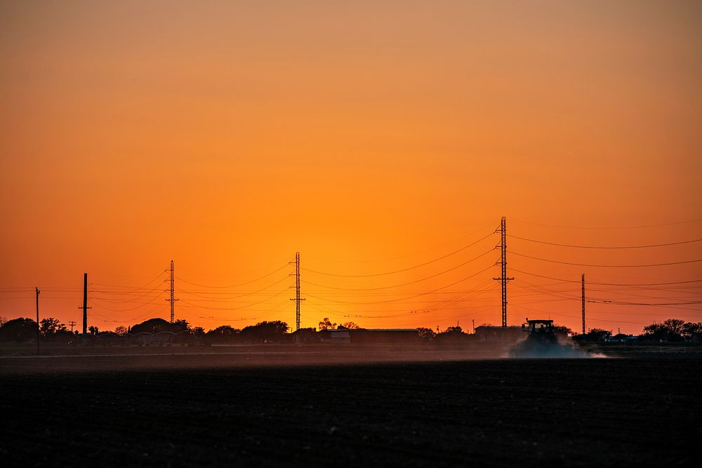 Sunset on a sprayer in the field, near power lines and towers, Hondo, Texas, on April 9, 2021. USDA Photo/Media by Lance…