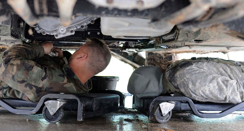Spc. Gregory Whited and Pfc. Miguel Vazquez work on a vehicle damaged during a patro at the Joint Multinational Readiness…