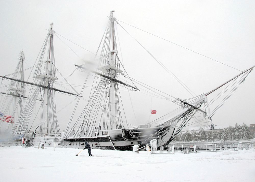 U.S. Navy Aviation Electrician's Mate Airman John Fisher shovels snow in front of USS Constitution moored in Charlestown…