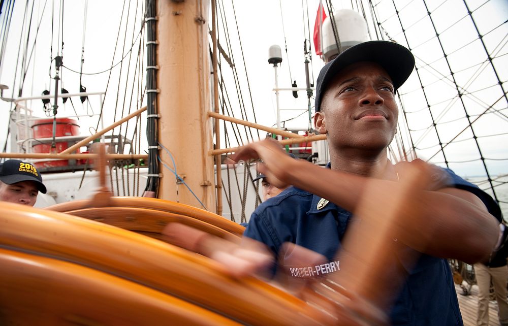 U.S. Coast Guard Academy Fourth Class Cadet Tevin Porter-Perry, 17, of Hampton, Va., turns the helm aboard the Coast Guard…