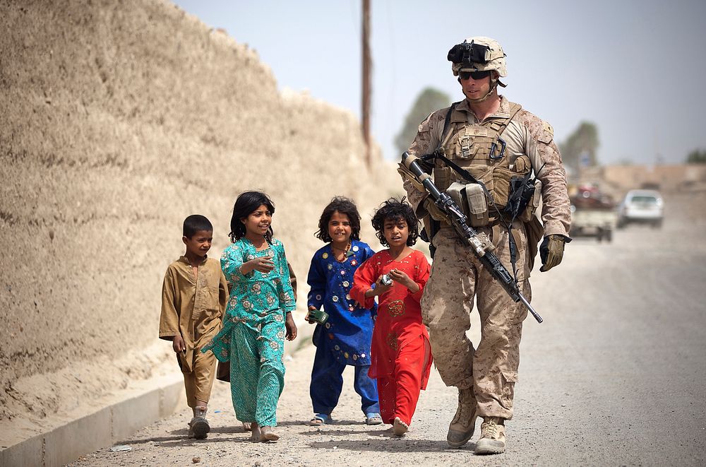 U.S. Marine Corps Lance Cpl. Jacob Kartchner, assigned to 3rd Battalion, 3rd Marine Regiment, walks with Afghan children…