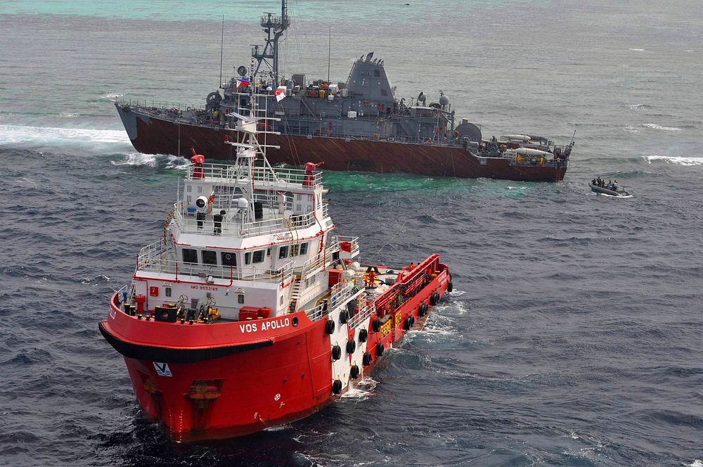The Malaysian tugboat VOS Apollo, front, prepares for defueling operations near the grounded mine countermeasures ship USS…