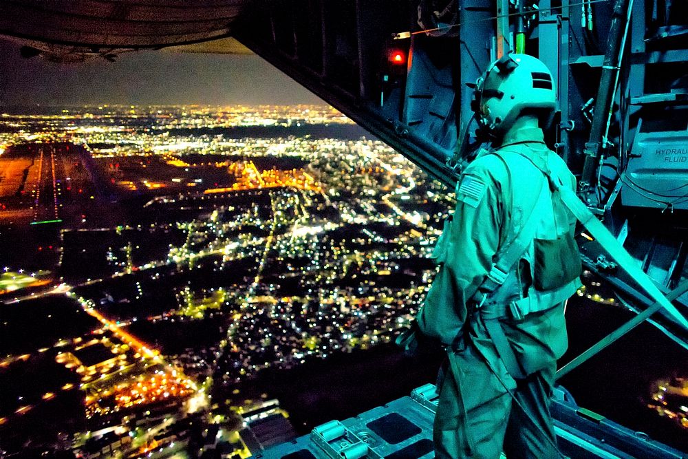 U.S. Air Force Staff Sgt. Nickolas Alarcon, a loadmaster assigned to the 36th Airlift Squadron, observes a drop zone from…
