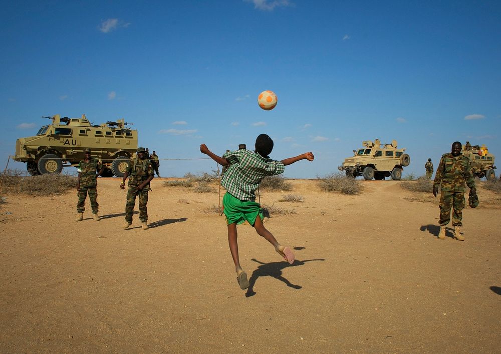 Ugandan soldiers serving with the African Union Mission in Somalia (AMISOM) play football with young Somali boys in the…
