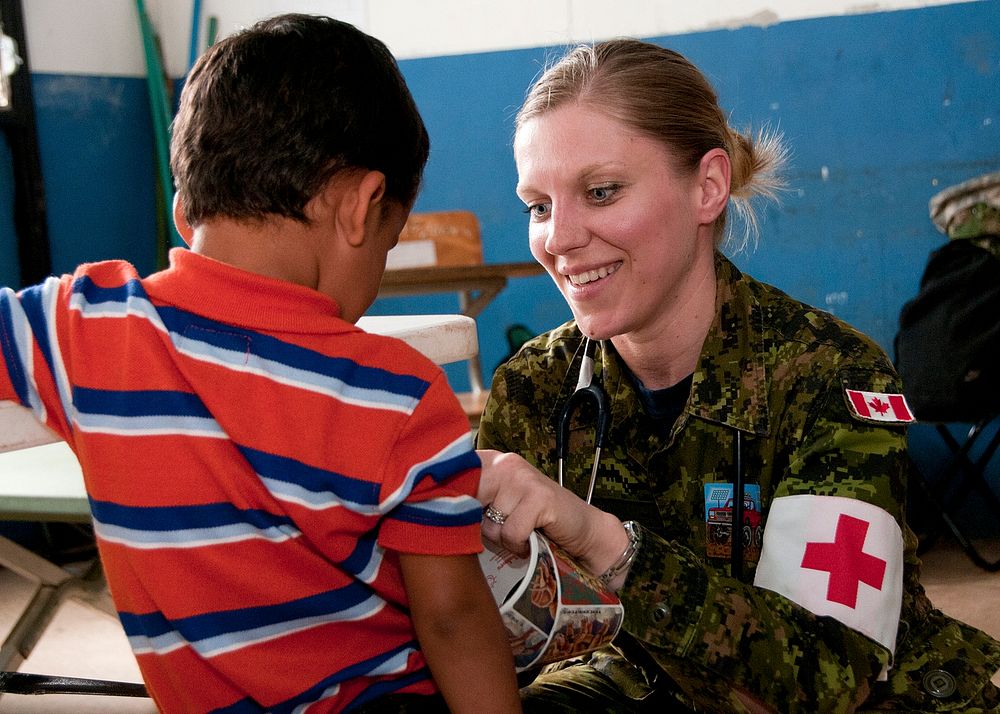 Canadian Forces Capt. Karoline Martin, a nurse with the Canadian Forces Health Services Center, gives a child a sticker…